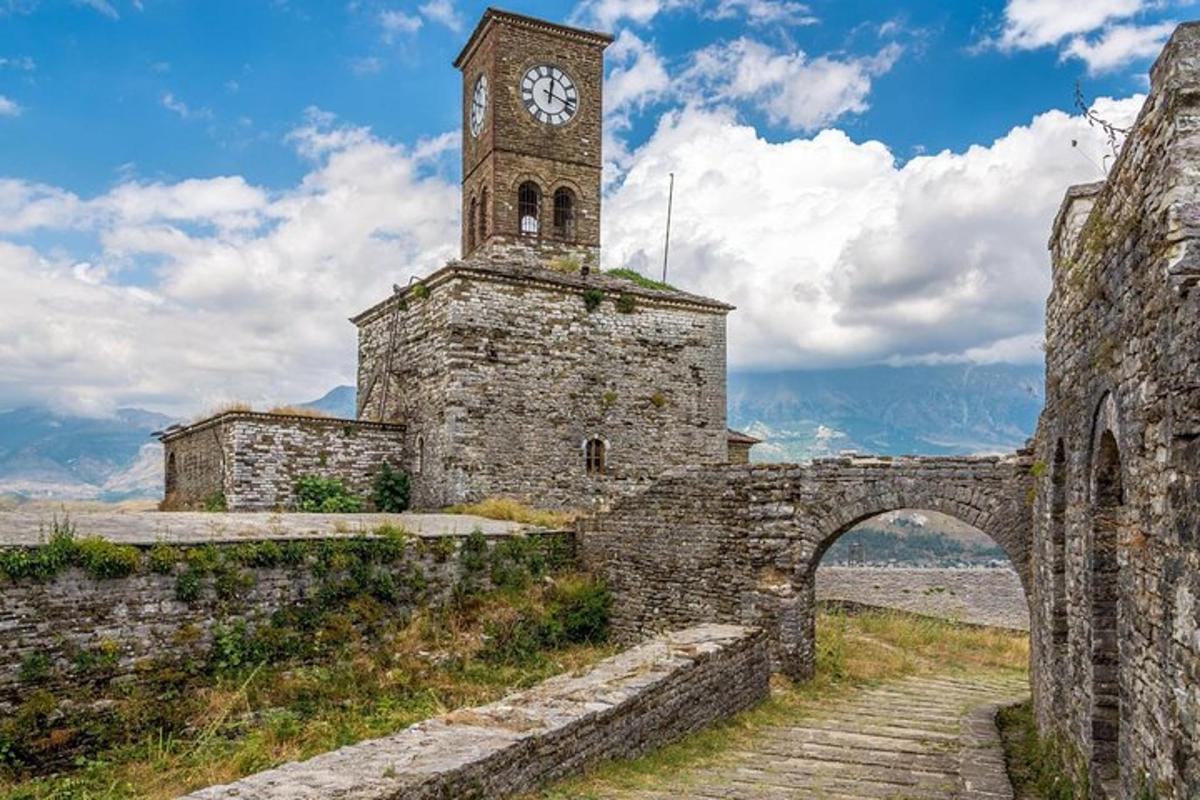 senas akmeninis pastatas su laikrodžio bokštu ir tiltu