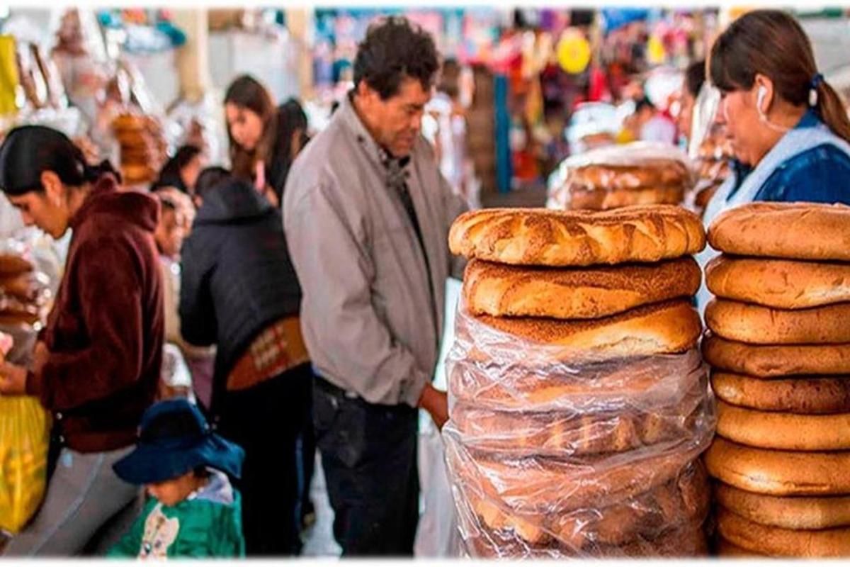 un gruppo di persone in piedi intorno a un mercato con il pane