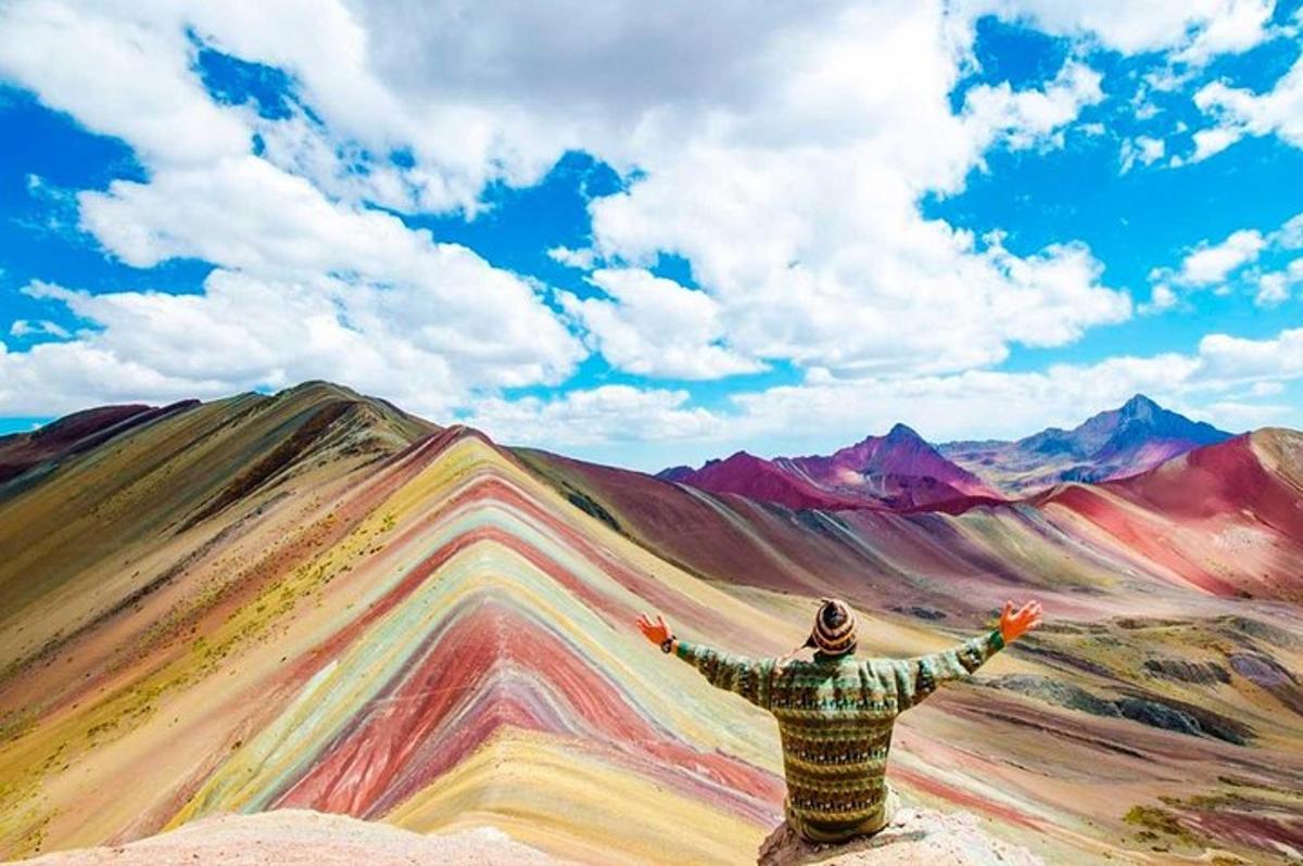 un uomo in piedi sulla cima di una montagna con le braccia tese