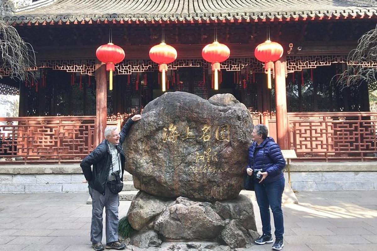 two people standing next to a rock in front of a temple