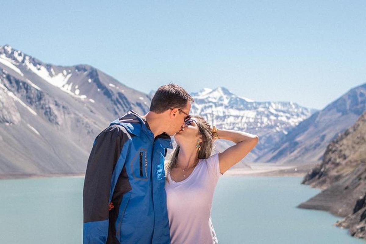 a man and a woman kissing in front of a lake