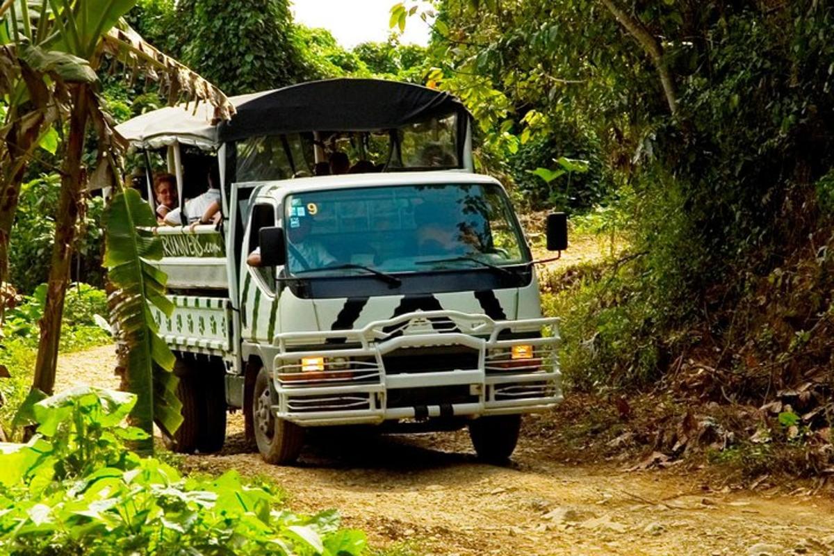 a green truck driving down a dirt road