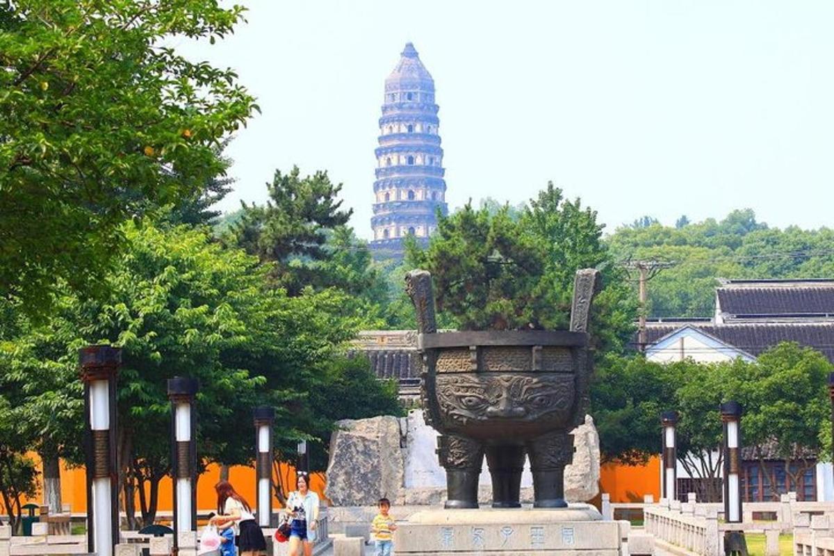 a large statue in a park with a tower in the background