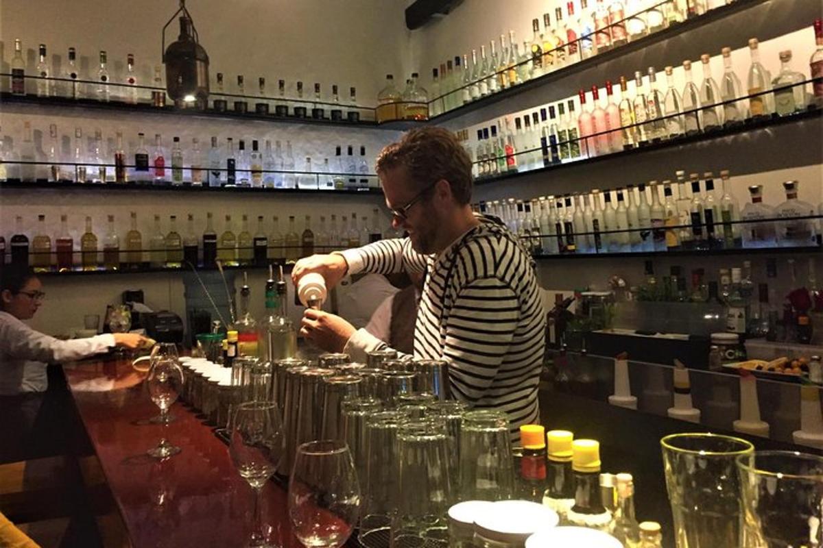 muž stojící u baru a připravující si drink