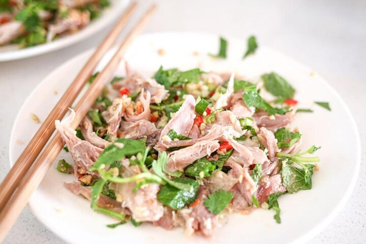 a white plate of food with meat and greens