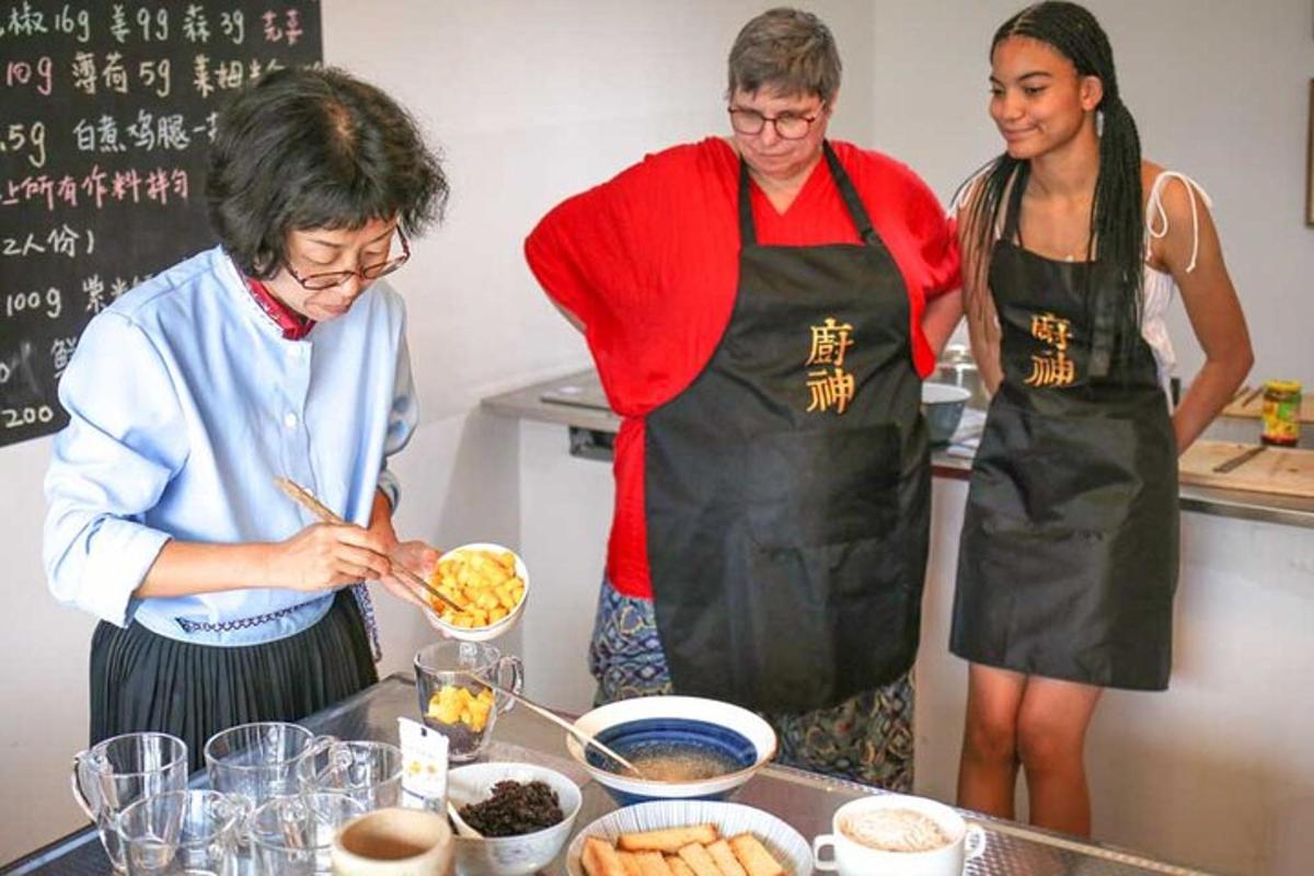 three women standing in a kitchen preparing food
