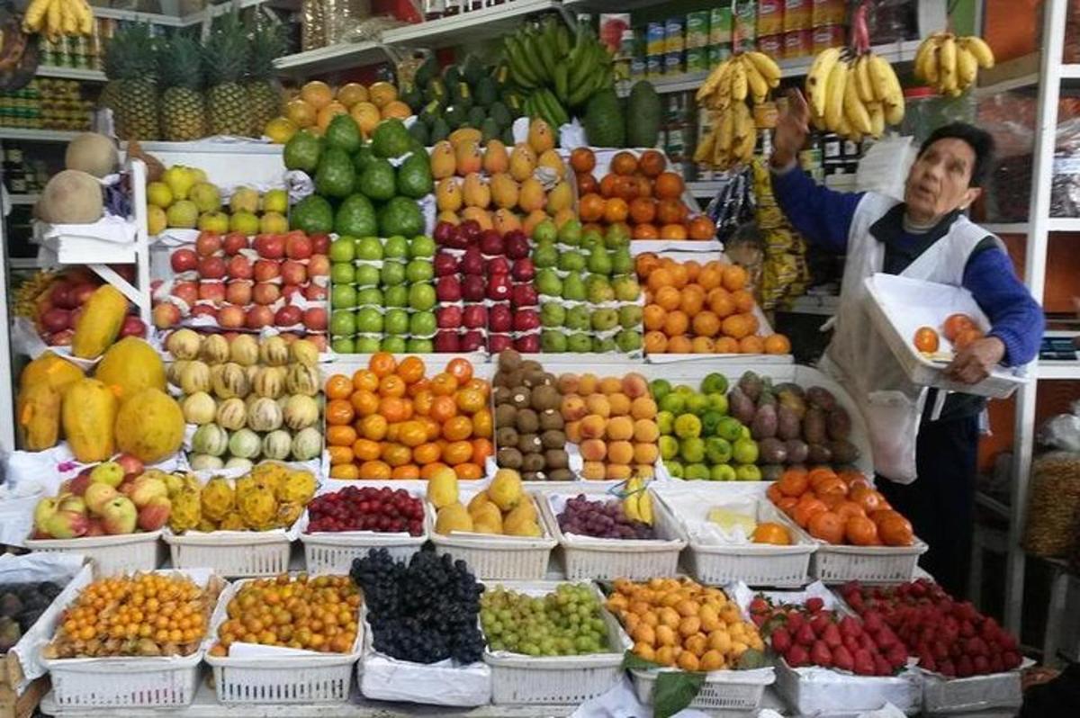 Un hombre parado frente a una exhibición de frutas.