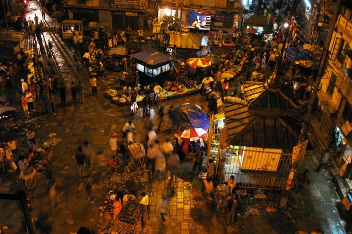 a crowd of people walking around a market at night