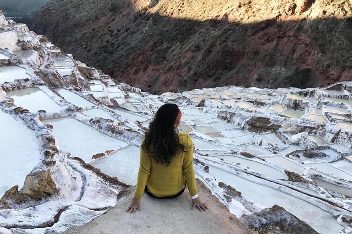 seorang wanita duduk di atas batu melihat gunung bersalji