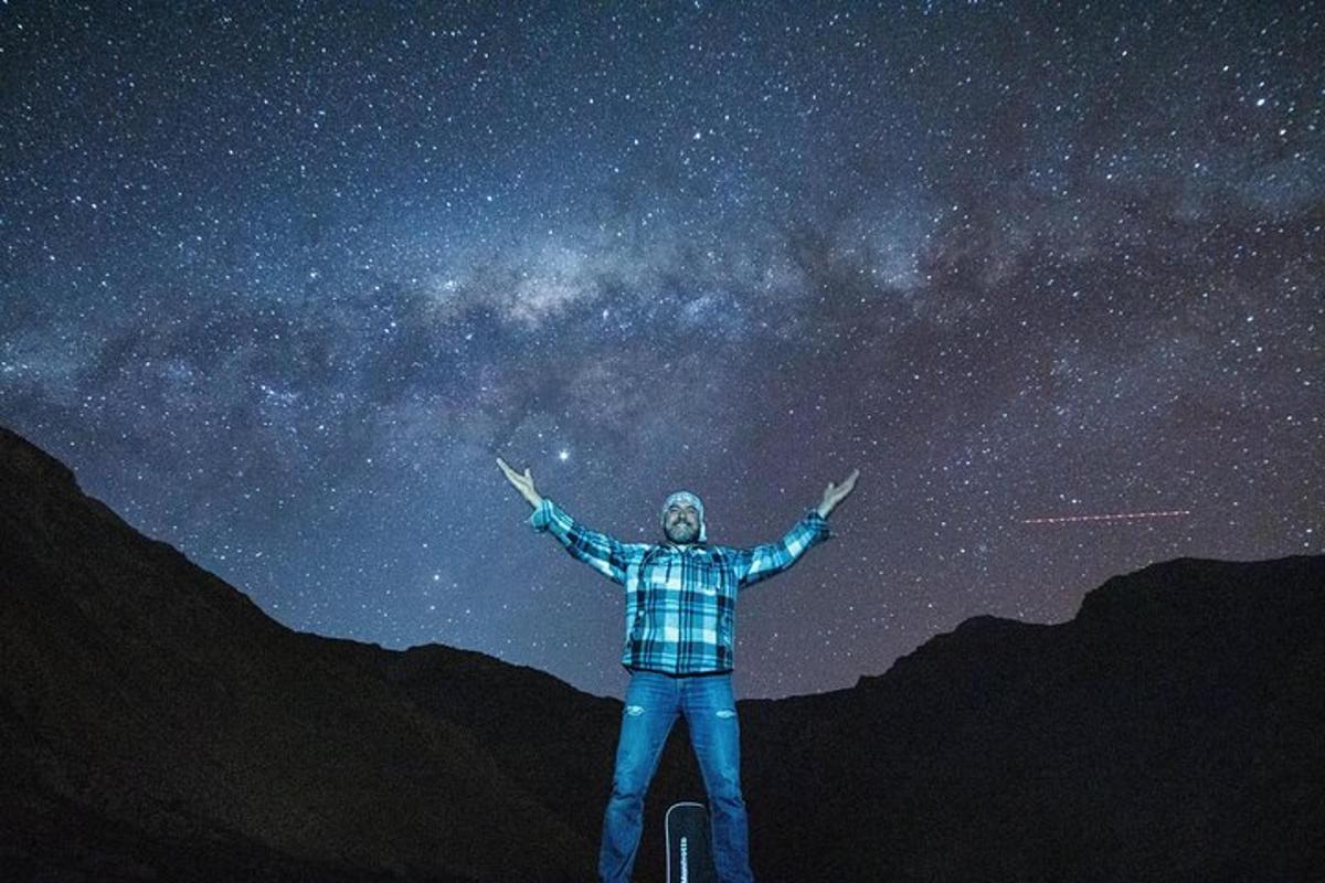a man standing on top of a mountain looking at the stars