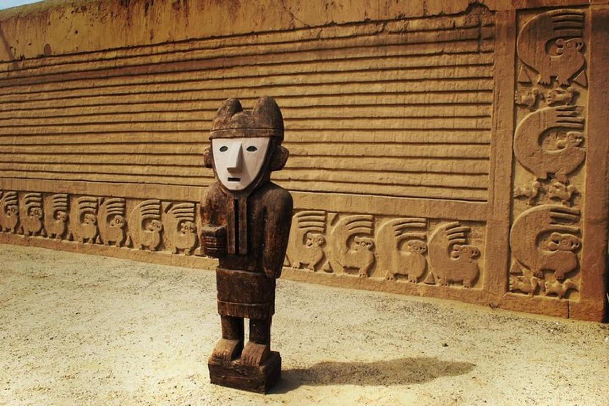a wooden statue of a person in front of a wall