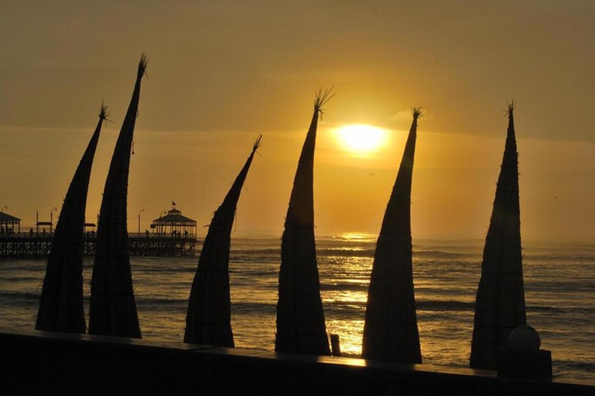a group of poles in the ocean with a pier in the background