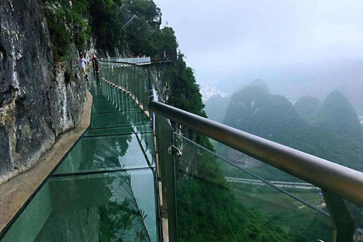 una passerella di vetro su una montagna con uno specchio d'acqua