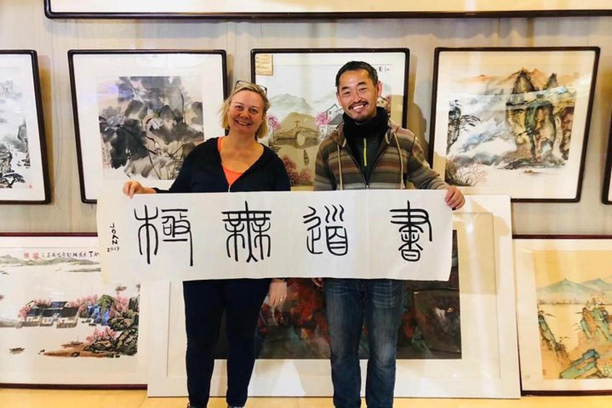 a man and woman holding a sign in front of paintings