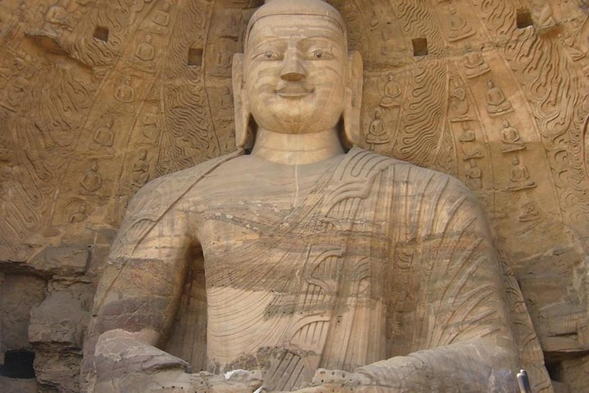 a statue of a man sitting in front of a wall