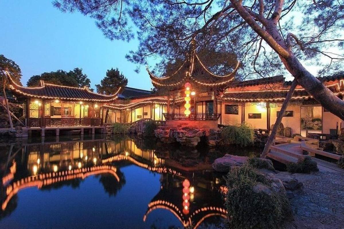 an asian house with a pond in front of it