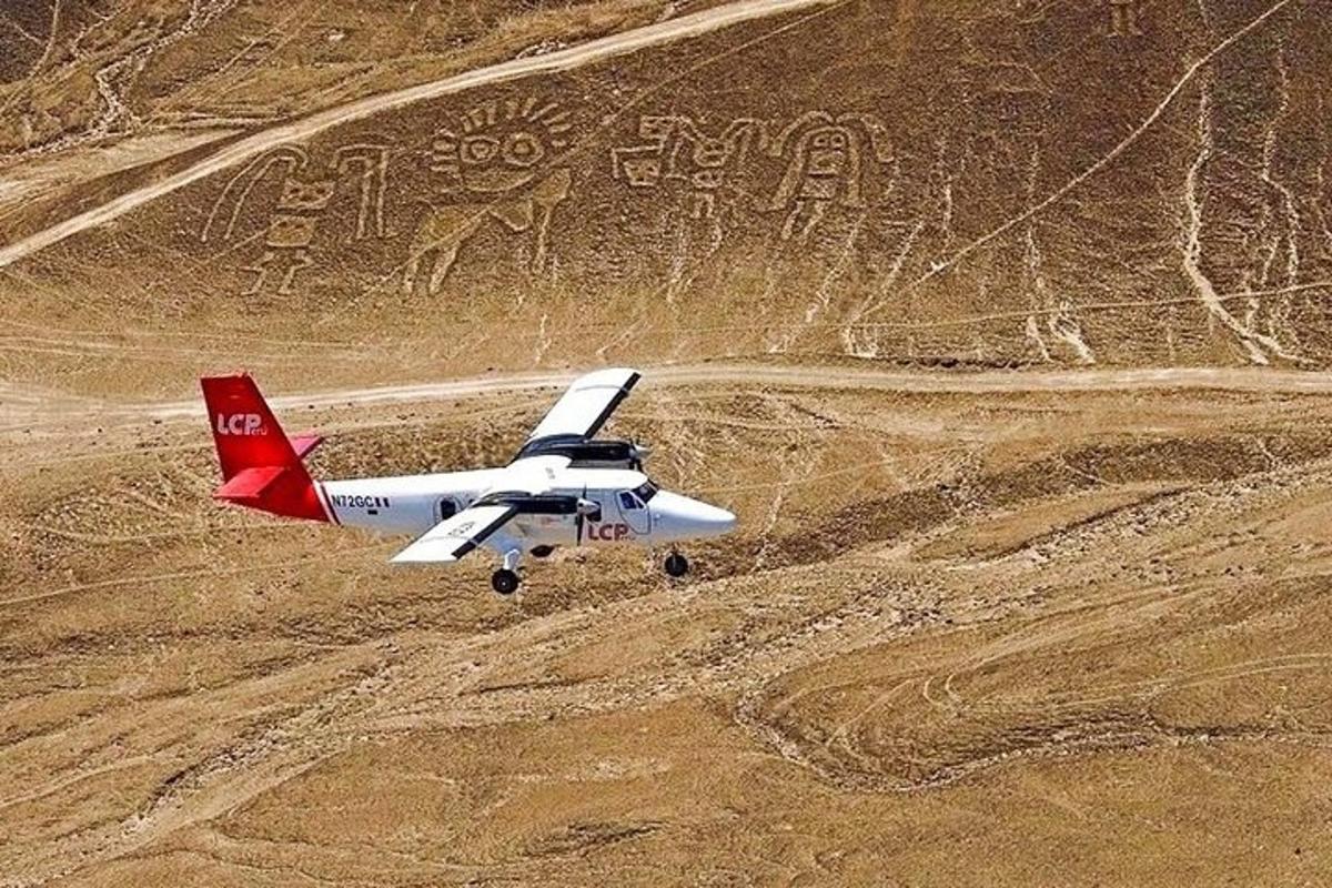 a small plane is flying over a dirt field
