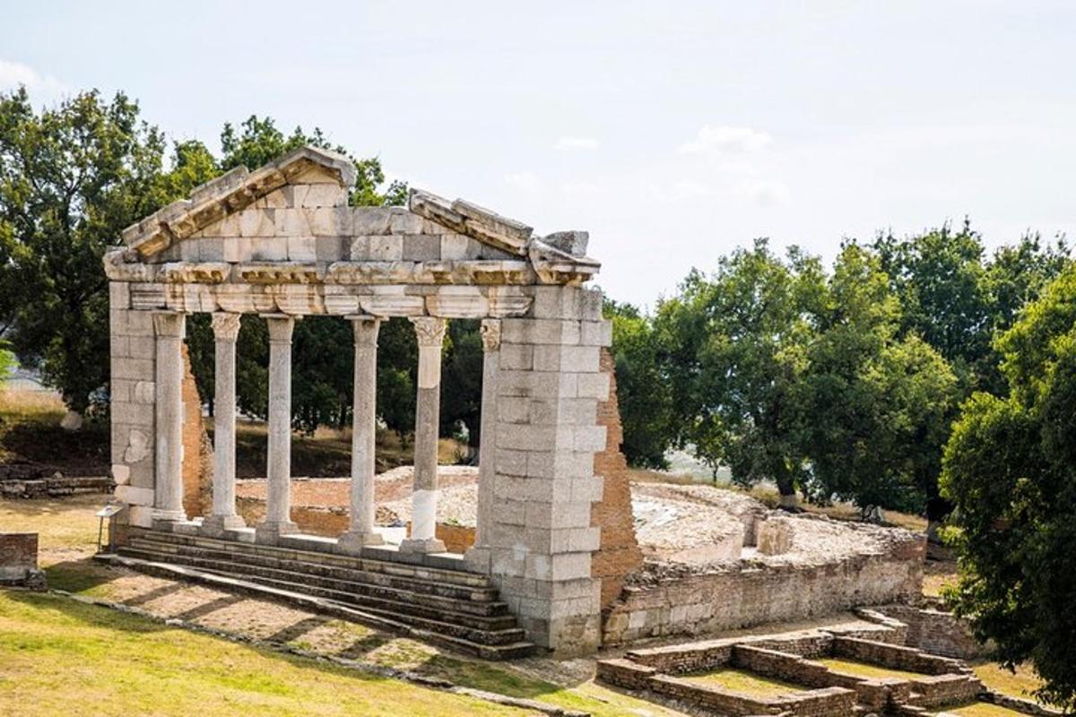 un piccolo edificio in pietra con colonne su un campo