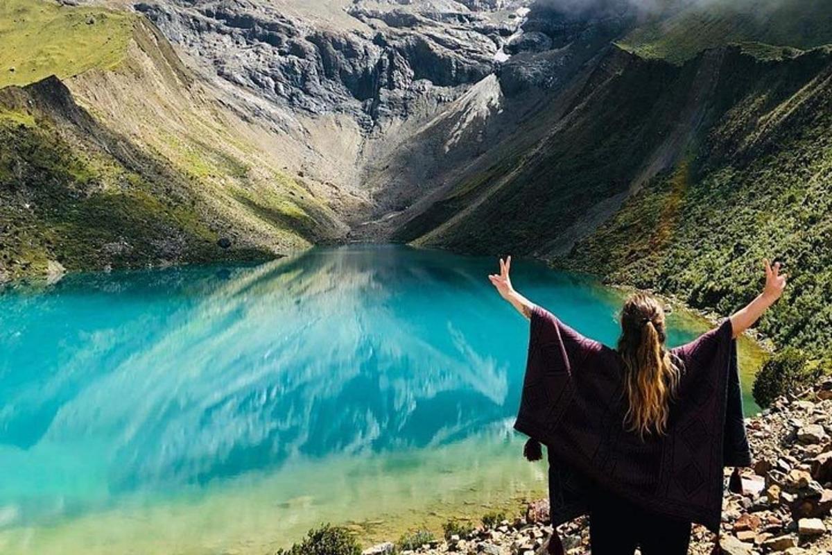 una donna in piedi sulla cima di una montagna che domina un lago