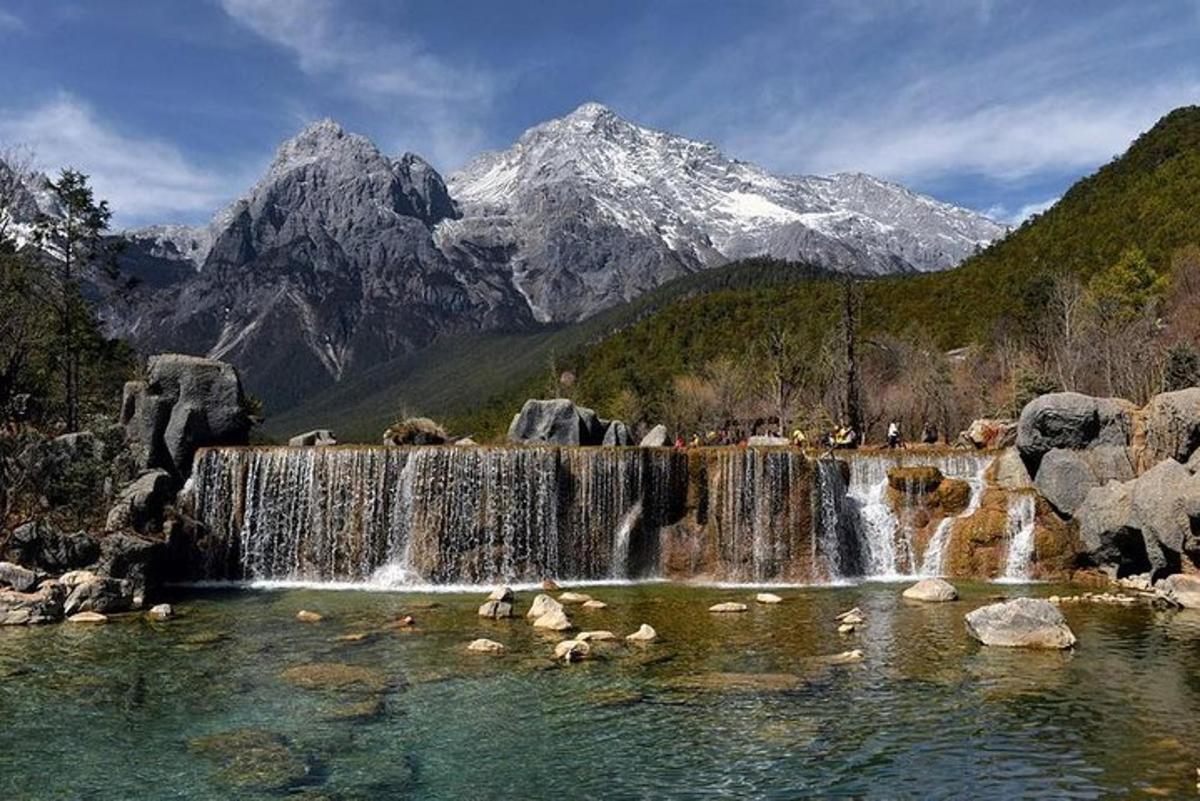 a waterfall in a river with mountains in the background