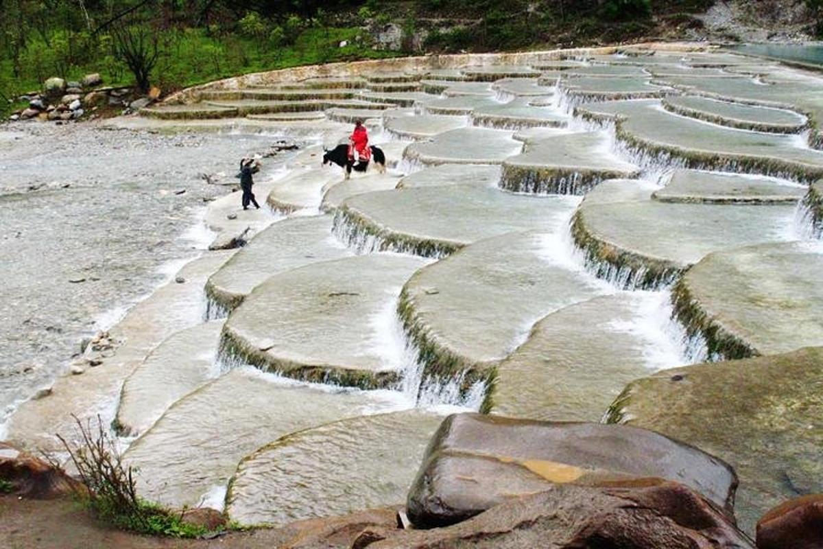 a group of rocks with people on horses in the water