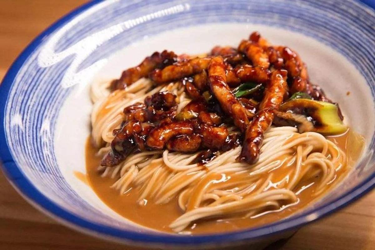 a blue and white bowl of food with noodles and meat