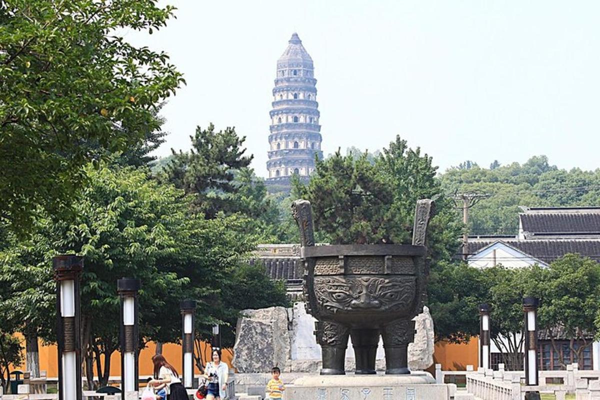 uma estátua em um parque com uma torre ao fundo