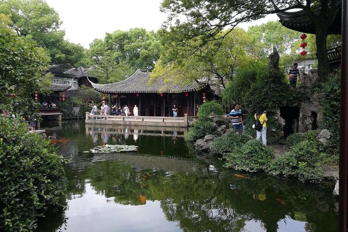 um lago em um jardim com pessoas em pé perto de um prédio