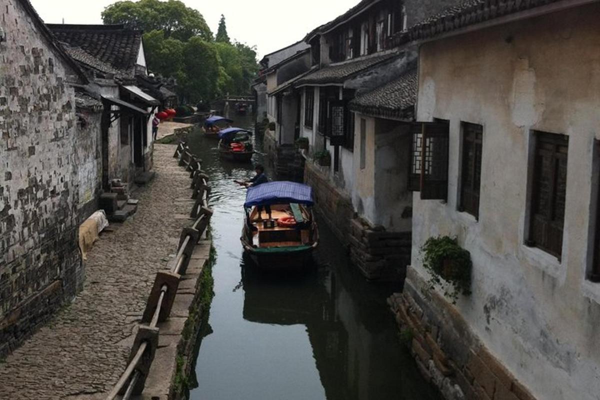 isang maliit na bangka sa isang kanal sa pagitan ng dalawang gusali