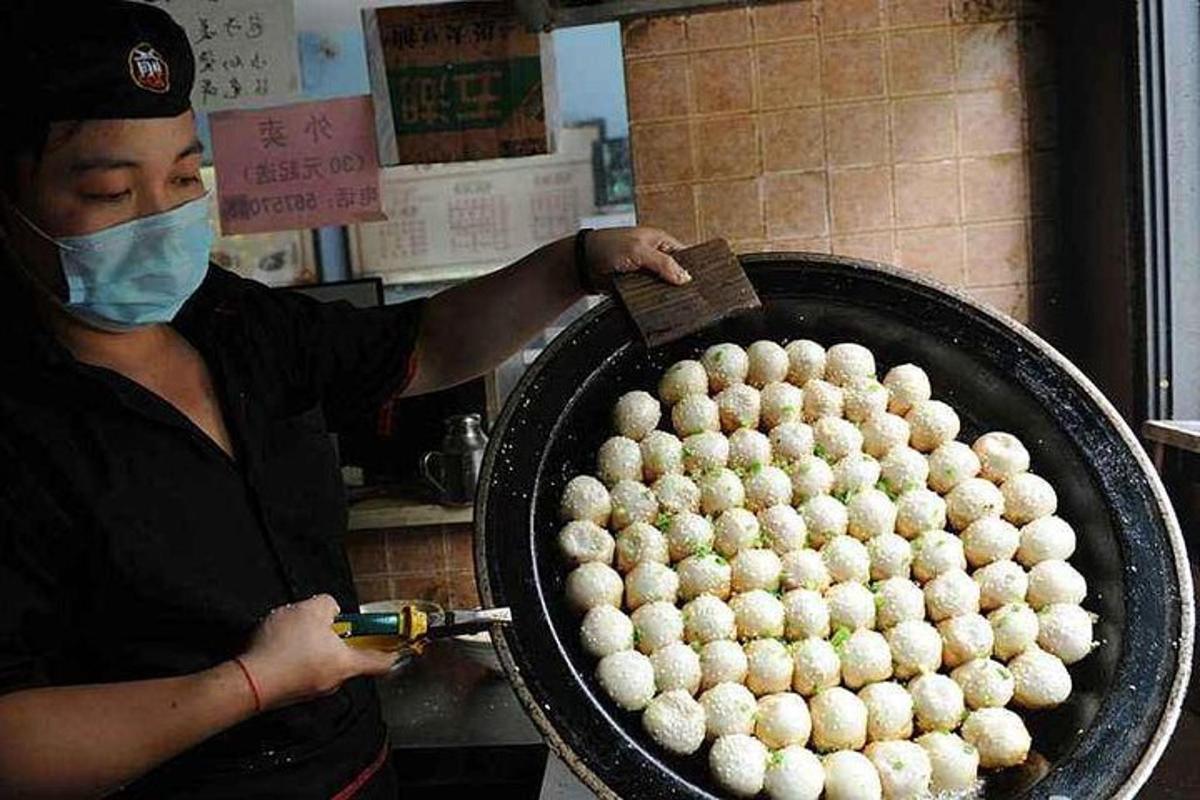 a woman wearing a mask holding a pan of balls