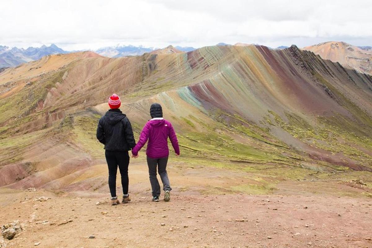 due persone che salgono su una montagna guardando un arcobaleno