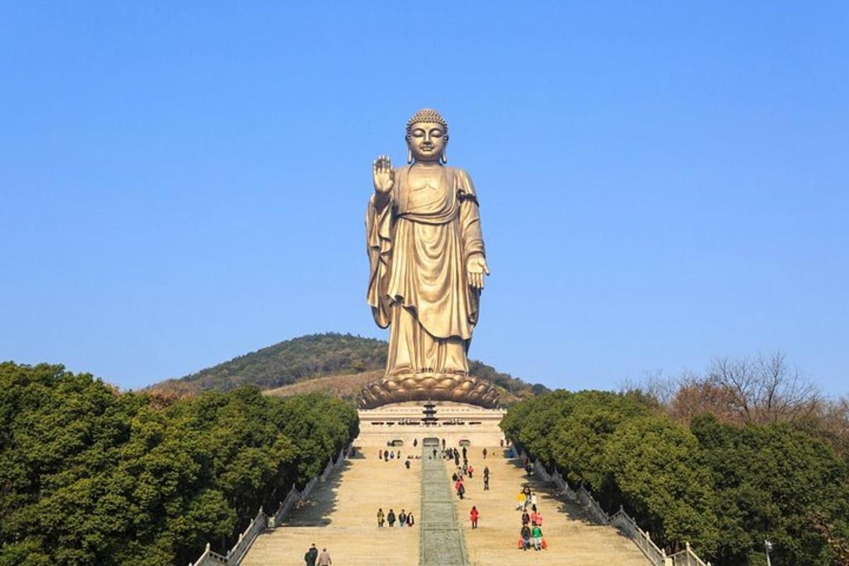 a large statue in a park with people walking around it