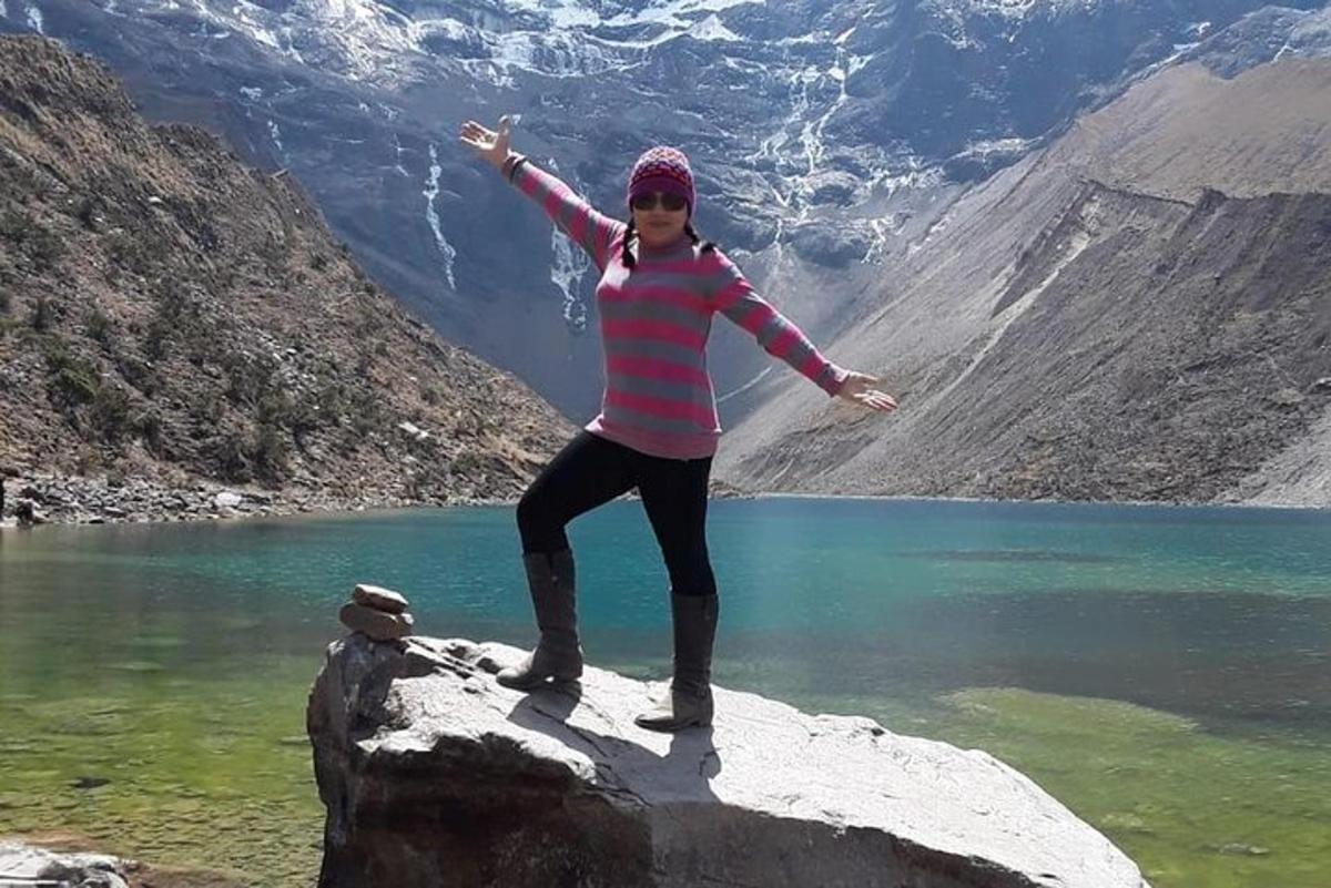 una donna in piedi su una roccia vicino a un lago
