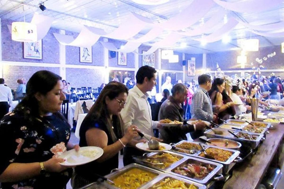 eine Gruppe von Menschen steht mit Essen an einem Buffet