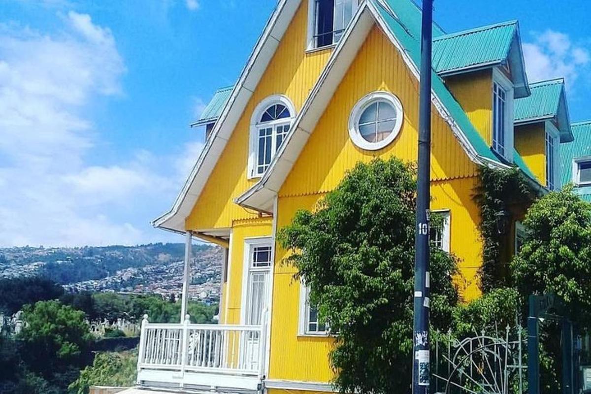 o casă galbenă cu un balcon alb pe un deal