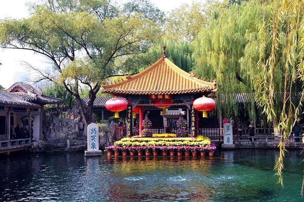a temple in the middle of a pond in a garden