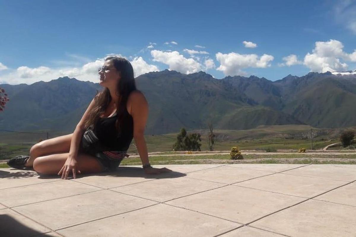 una donna seduta a terra con le montagne sullo sfondo