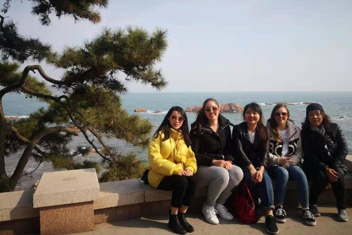 a group of women sitting on a bench near the ocean