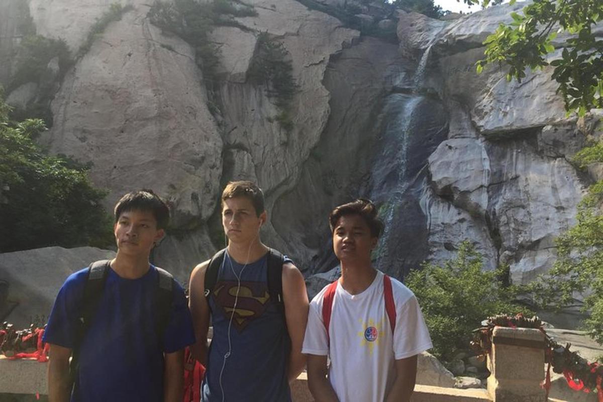 three young men standing in front of a waterfall