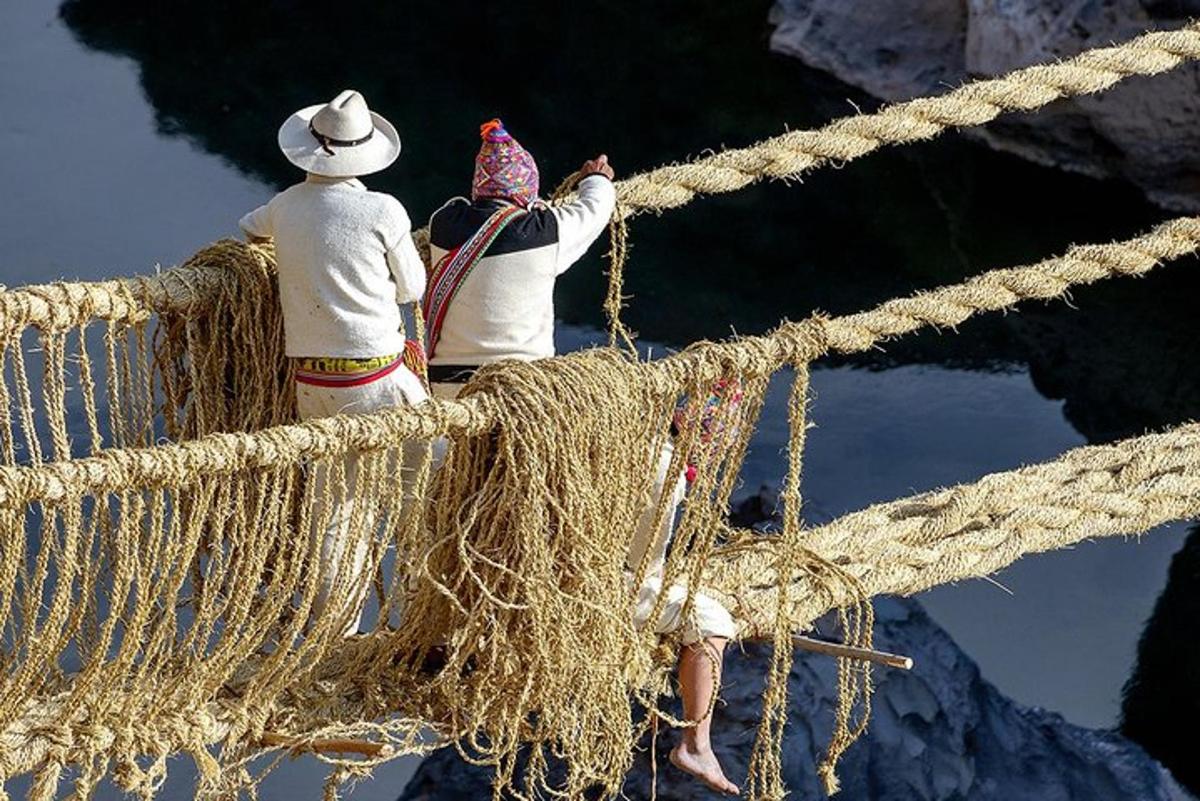 two people sitting on a rope looking at the water