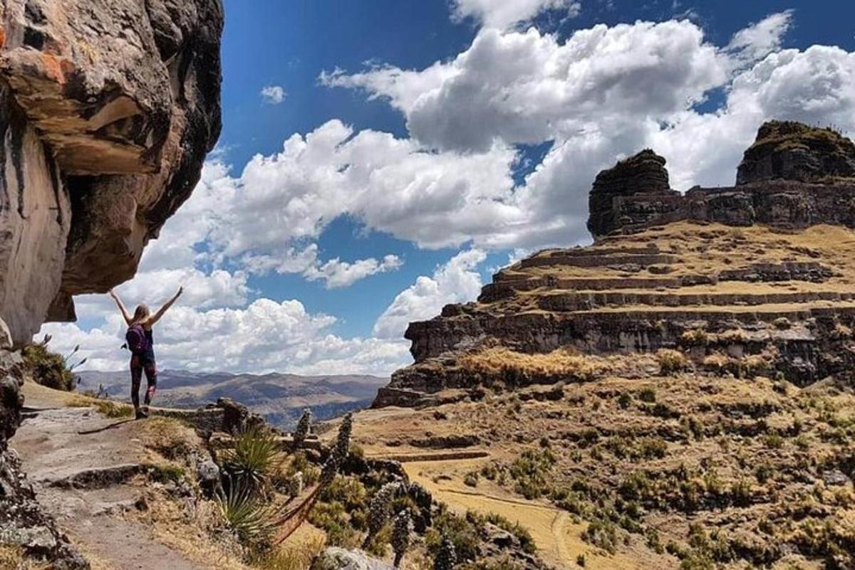 um homem em pé na encosta de uma montanha com os braços levantados