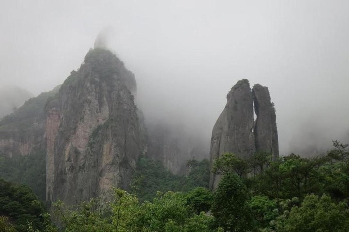 a group of large rocky mountains in the fog