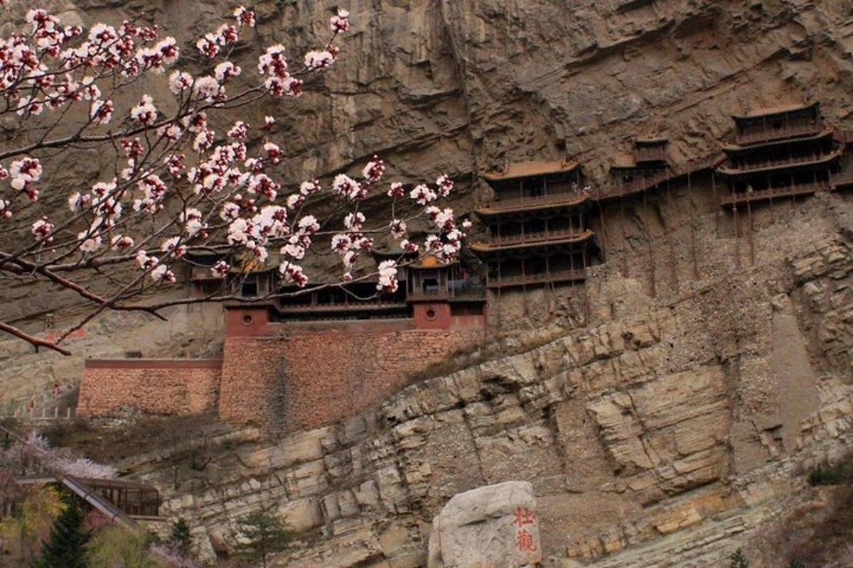 a building on the side of a mountain with pink flowers