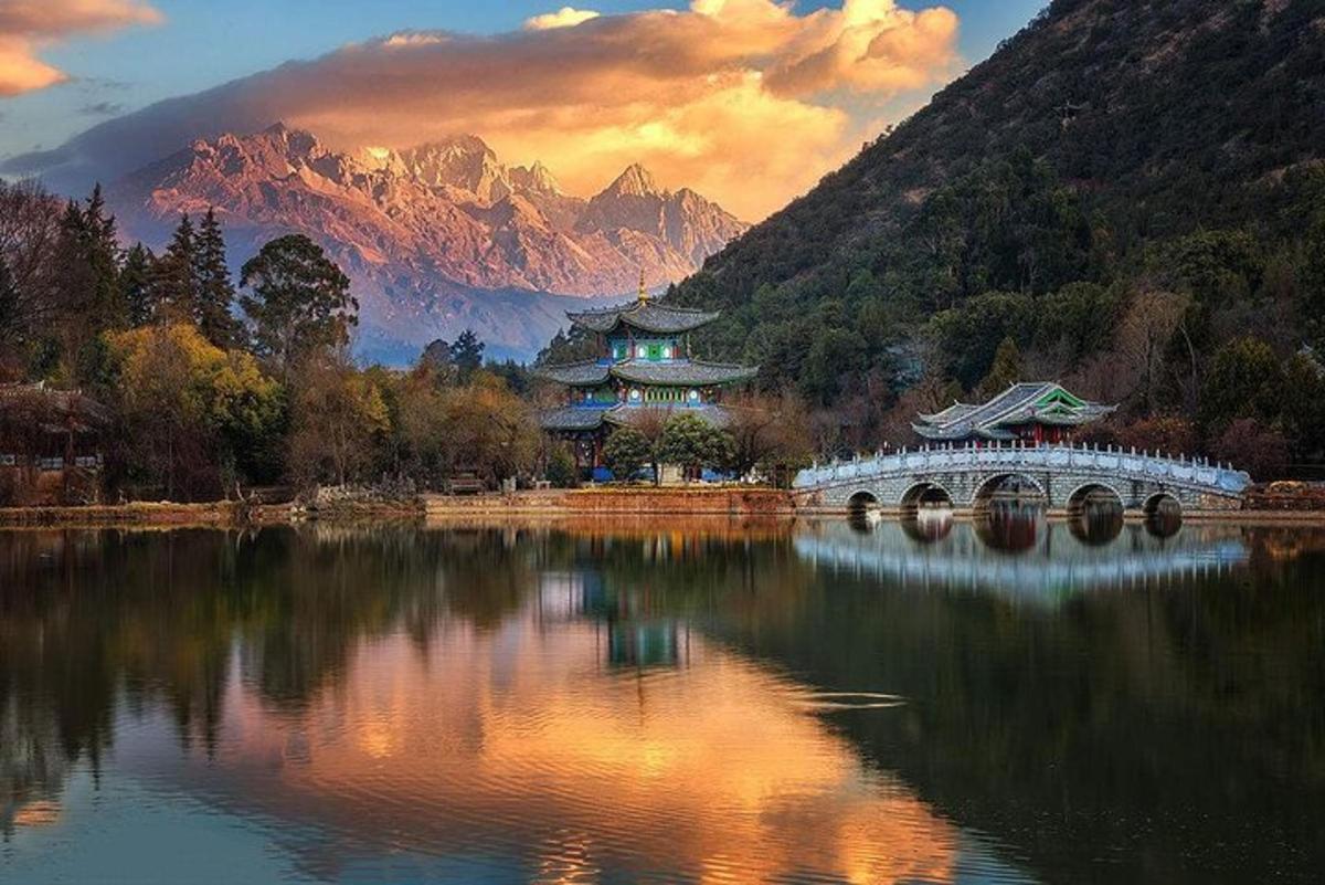 a lake with a bridge and mountains in the background