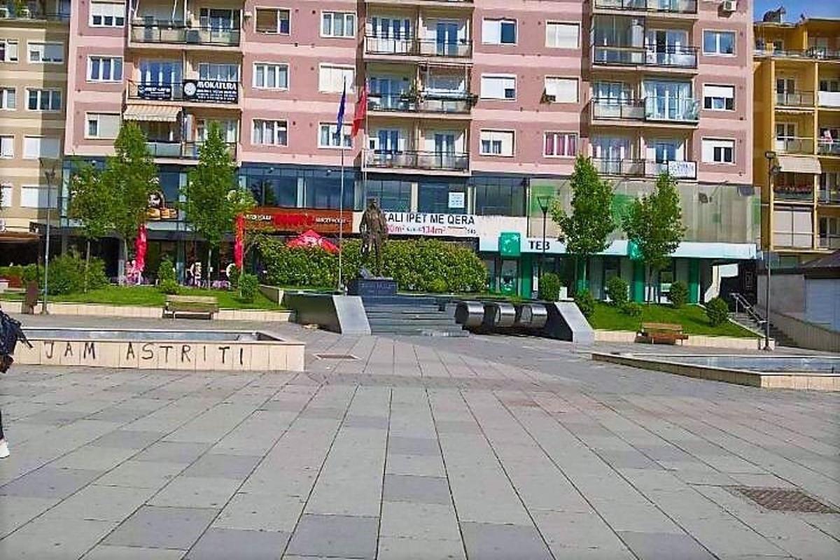 osoba kráčející před růžovou budovou