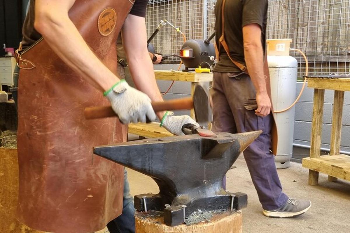 two men are working on avil in a forge