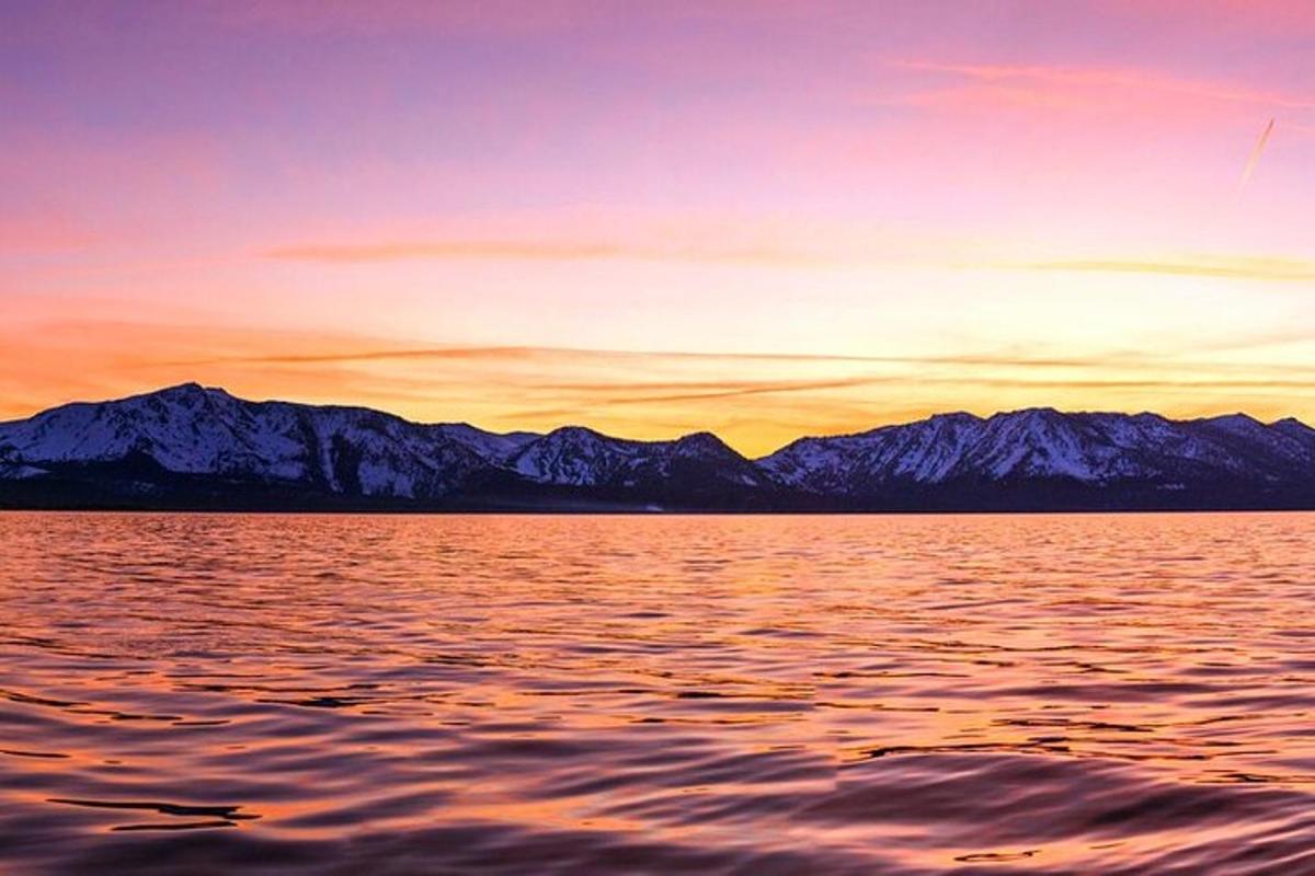 a sunset over a large body of water with mountains