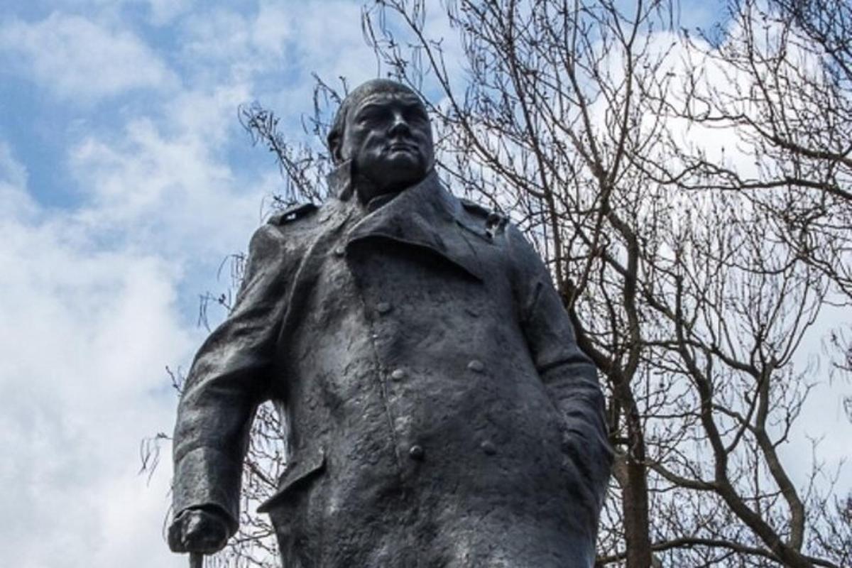a statue of a man standing next to a tree