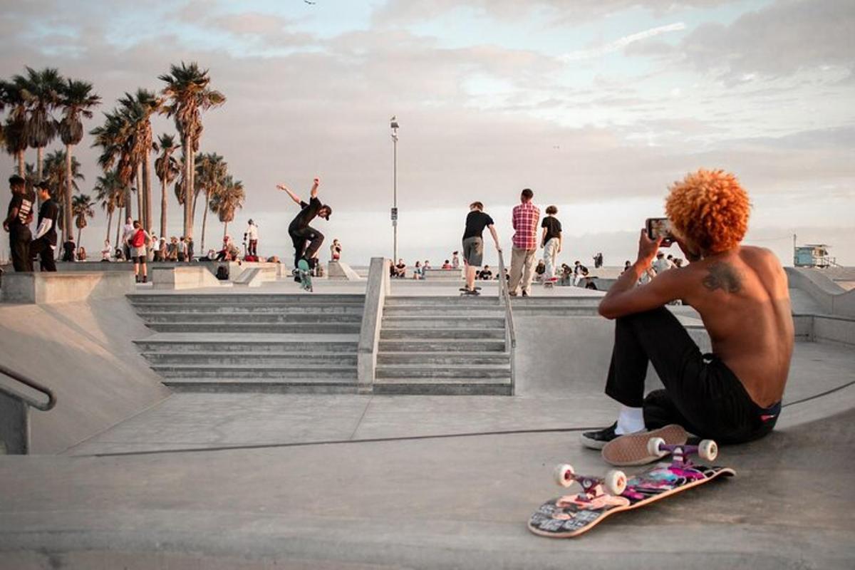 muž sedící na zemi a fotící skateboard