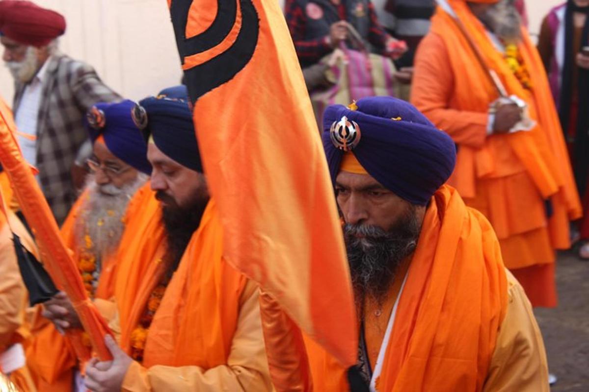 a group of men wearing orange turbans holding a flag